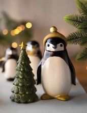 Christmas penguins figurines celebrating winter holidays with a lighted tree and blurred lights, AI
