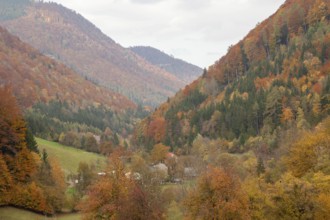 View of the valley with colourful autumn forests and a small village in the middle of the