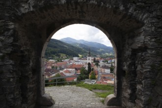 View through a stone Tor tor to a town with church tower and surrounding mountains, Bruck an der