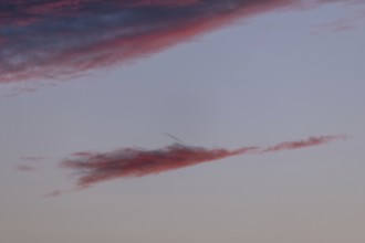 Colourful clouds form in the evening sky and present shades of red and blue. This natural spectacle