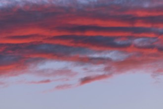 Colourful clouds form in the evening sky and present shades of red and blue. This natural spectacle