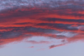 Colourful clouds form in the evening sky and present shades of red and blue. This natural spectacle