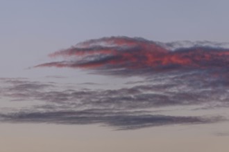 Colourful clouds form in the evening sky and present shades of red and blue. This natural spectacle
