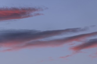 Colourful clouds form in the evening sky and present shades of red and blue. This natural spectacle