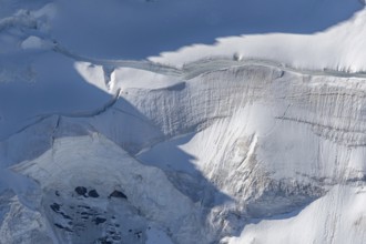 A large blanket of snow covers the rocks in the mountains. The sky is clear and reflects the serene
