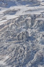 The mountainous landscape reveals impressive glaciers with ice formations and gleaming reflections