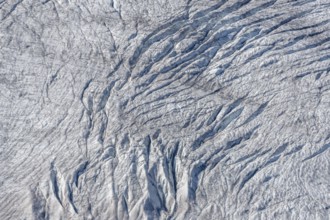 Crevices mark the surface of the glacier. The landscape is illuminated by daylight, highlighting