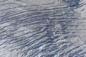Crevices mark the surface of the glacier. The landscape is illuminated by daylight, highlighting