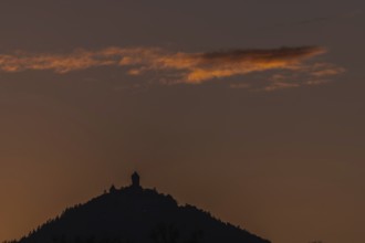 The top of the mountain is cut off against the orange-coloured sky at sunset. The soft light