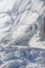 Broad alpine landscape shows glaciers and snow deposits. The mountains are visible in the