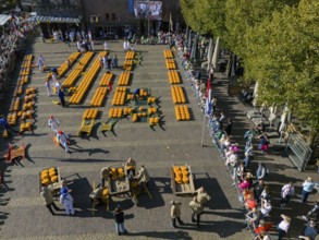 Traditional Dutch cheese market scene with rows of cheese, watched by numerous spectators, aerial