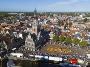 Historic city view with a tower and a busy cheese market in the old town centre, aerial view,