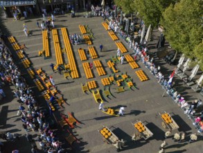 A traditional Dutch cheese market with many people and cheese arranged in rows, aerial view,
