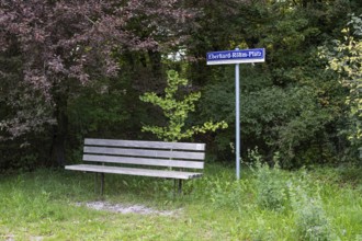 Wooden bench in front of a sign with the inscription Eberhard-Röhm-Platz, square named after a