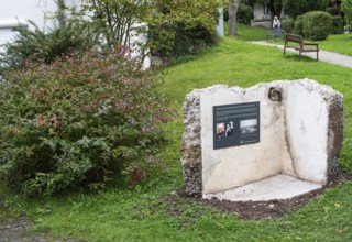 Memorial plaque with photos of a former concentration camp inmate, remains of the walls of a