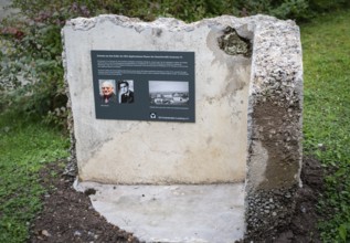 Memorial plaque with photos of a former concentration camp inmate, remains of the walls of a