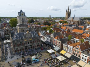 View of the city centre with town hall and lively market square full of people, aerial view, town