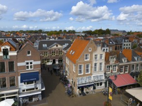 Urban street scene with shops, old buildings and bicycles under a cloudy sky, aerial view, houses