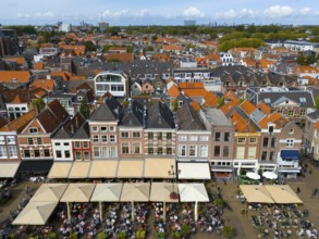 Row of town houses with red roofs and lively restaurant area in the foreground, aerial view,