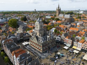 Town hall with tower, surrounded by historic buildings and lively market life, aerial view, town