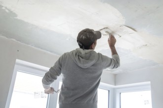 Plasterer levelling and smoothing the ceiling in the interior
