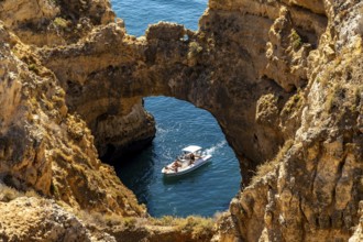 Excursion boats at the caves and rocky gates of the Ponta da Piedade rocky coast, rugged coastal