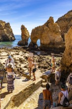 Tourists at the caves and rocky gates of the Ponta da Piedade rocky coast, rugged coastal