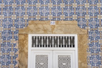 Facade of buildings decorated with tiles, azulejos, coloured tiles on facades, in Tavira, old town,