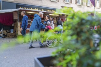 People strolling and some pushing a wheelchair along a busy market street, Sindelfingen, Böblingen