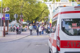 An ambulance parked near a busy market square with a crowd of people, Sindelfingen, Böblingen