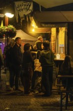 People standing at night at an illuminated food stall in a park, Sindelfingen, Böblingen district,