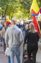 People walking along a crowded street surrounded by trees and autumn leaves, Sindelfingen,