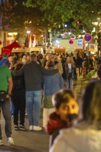 Large group of people at night in a busy urban environment with festive lighting, Sindelfingen,