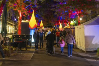 People strolling on a colourful, festive street at night with illuminated trees, Sindelfingen,