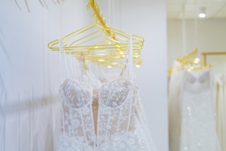 Row of white wedding dresses made of filigree lace presented on yellow hangers, Sindelfingen,