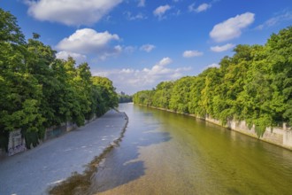 A river flows between lush green trees under a clear sky, Munich, Germany