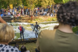 Surfers prepare for water riding on the river bank while spectators watch, Munich, Germany
