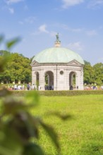 Historic pavilion with green dome in a meadow, people walking surrounded by nature, Munich, Germany