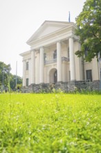 Building with white columns and large windows on a green lawn on a sunny day, Munich, Germany