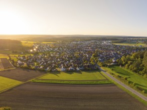 Aerial view of a village and its surroundings with fields and rural landscape at sunset,