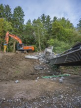An excavator is demolishing a bridge in a wooded area, bridge demolition, Calw, Germany