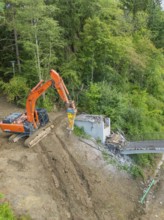 An excavator works on the dismantling of a bridge in a wooded area, bridge demolition, Calw,