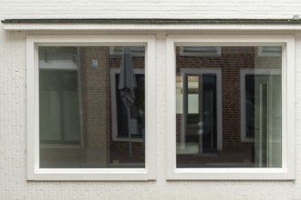 TBorken, NRW, Germany, wo large windows are reflecting a brick building and a parasol on a white