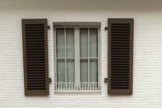 Borken, NRW, Germany, Brown shutters are closed over a window with a white security bar on a white