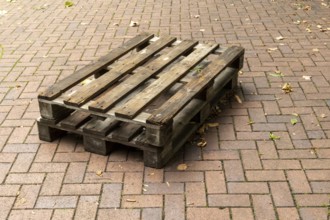 Borken, NRW, Germany, Two weathered wooden pallets are placed on a herringbone brick pavement,