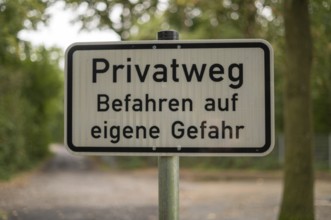 Borken, NRW, Germany, German warning sign privatweg befahren auf eigene gefahr on a pole in a
