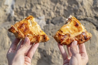 Two slices of maltese pizza hold in the woman's hands with stone background, Gozo, Malta