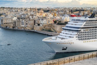 Beautiful sunset view of Valletta with a cruiser in the foreground, capital city of Malta