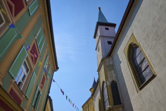 Building with coloured flags, church tower and historical architecture under the sky, Regensburg,