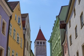 Colourful buildings and church tower along a busy street under a clear sky, Regensburg, Bavaria,